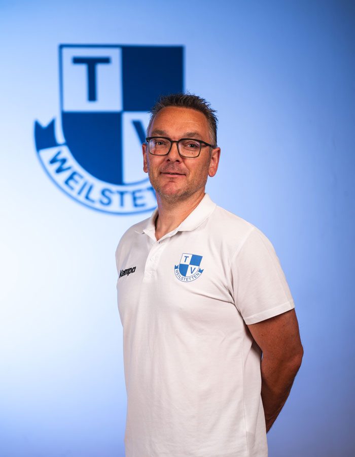 Portrait Abteilungsleiter Handball vor Wand mit Logo